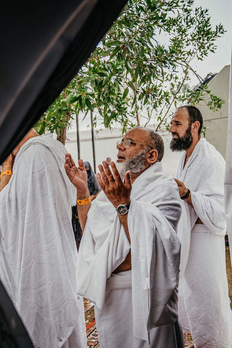 A group of men in white robes participate in a spiritual prayer outdoors, embracing cultural and religious traditions.